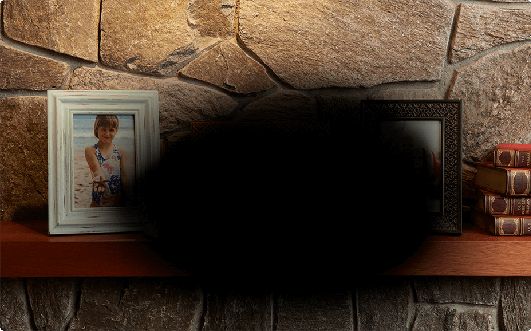 framed pictures on a mantel with black spot blocking view